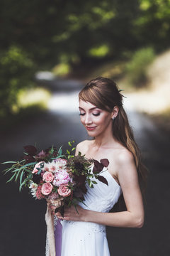 Portrait of bride close up with wedding bouquet with silk ribbons