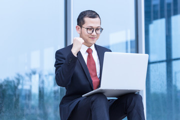 young businessman sitting on steps and using his laptop.