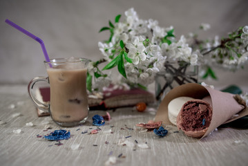 A book for notes with a pencil with hot cocoa in flower petals and crusshed macaroons