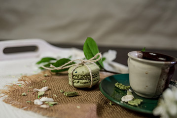 A cup of coffee on a white tray with branch of blossomed cherry and monstera leaf