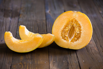 Half melon and slices on a dark wooden background