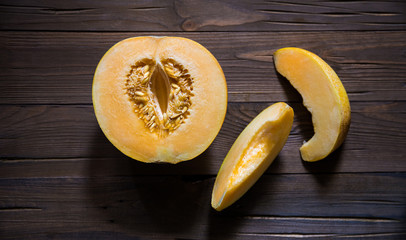 Half melon and slices on a dark wooden background