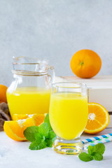 Fototapeta na wymiar A refreshing summer drink with orange juice, fresh oranges and mint on a gray stone or slate background.