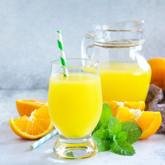 A refreshing summer drink with orange juice, fresh oranges and mint on a gray stone or slate background. The concept of healthy and dietary nutrition.