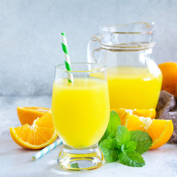 A refreshing summer drink with orange juice, fresh oranges and mint on a gray stone or slate background. The concept of healthy and dietary nutrition.