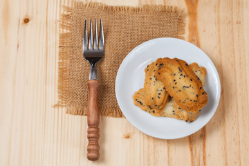 Home made a small sweet cookie with black sesame, typically round, flat, and crisp.Cookie in dish on wood.