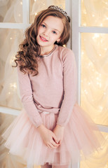 Full length portrait of happy young girl in a dress, standing with folded hands. World Smile Day.