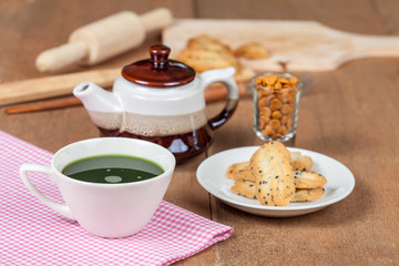 Hot and fresh green tea on wood with home made a small sweet cookie with black sesame.
