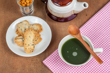 Hot and fresh green tea on wood with home made a small sweet cookie with black sesame.