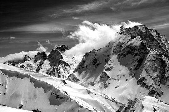 Black and white winter mountains with snow cornice and cloudy sky in nice sun day
