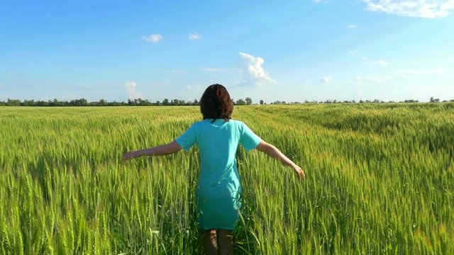 Beauty girl running on green wheat field.