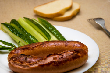 Fried sausage and cucumbers on a white plate.
