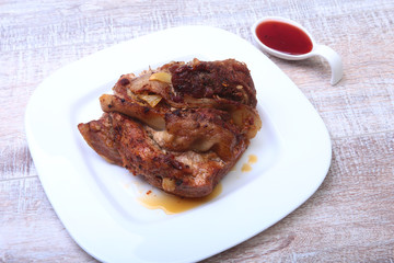 Steak of grilled meat with red sauce on white plate.
