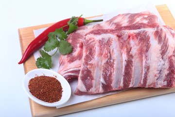 Raw pork ribs with herbs and spices on wooden board. Ready for cooking.