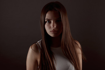 Belle jeune fille brune posant sur un fond gris 