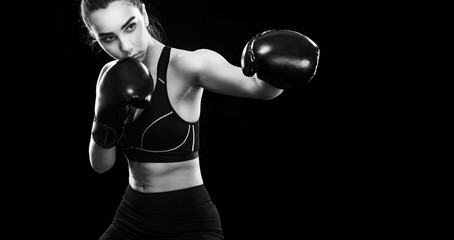 Woman boxer fighting in boxing cage. Isolated on black background. Copy Space. Black and white photo. Sport concept.