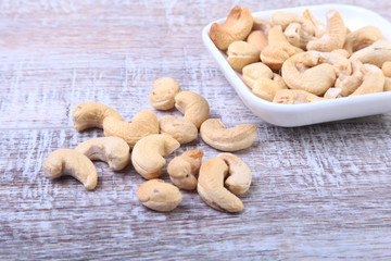 nuts cashews in white bowl on wooden background. Selective focus.