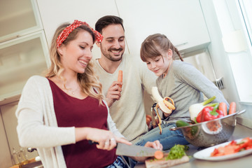 Young family preparing salad together.