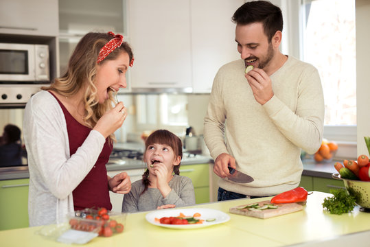 Young family preparing salad together.