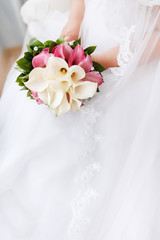 Close-up of a bride holding a wedding bouquet with flowers calla