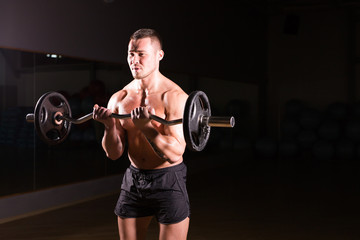 Fototapeta na wymiar Muscular man working out in gym doing exercises with barbell at biceps, strong male naked torso abs