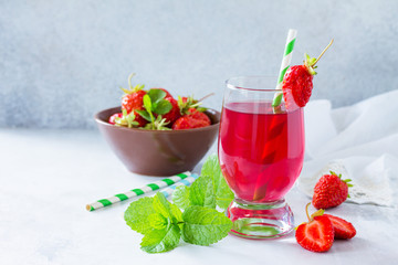 Refreshing summer drink strawberry juice, fresh strawberries and mint on a gray stone or slate background. The concept of healthy and dietary nutrition. Copy space.
