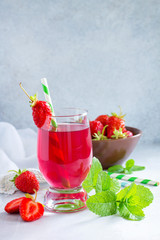 Refreshing summer drink strawberry juice, fresh strawberries and mint on a gray stone or slate background. The concept of healthy and dietary nutrition. Copy space.