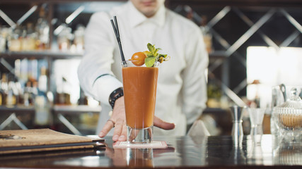 Bartender in hat is preparing cocktail in bar