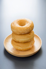 Sugary donuts on a wooden plate on a dark table background. in a Morning light. Breakfast concept