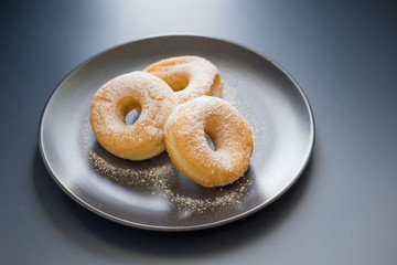 Sugary donut on a black plate on a dark table background. in a windows light. Breakfast concept