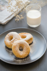Sugary donut on a black plate and glass of milk on a dark table background. in a windows light. Breakfast concept