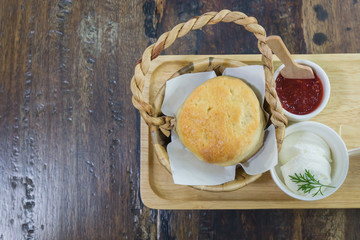 Scones with blueberry jam on wooden plate.