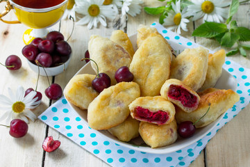 Fried pies. Pies sweet with cherries on the kitchen table in a rustic style.