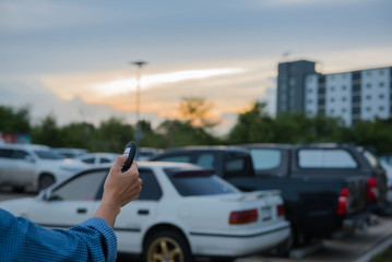 Fototapeta premium remote control key Car in hand In the outdoor parking lot at evening , system automatic. 