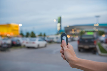 remote control  key Car in hand In the outdoor parking lot at evening  , system automatic. 