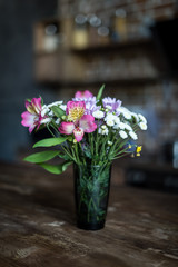 still life with bouquet of summer flowers in vase standing on wooden table