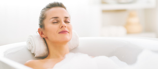 Obraz na płótnie Canvas Happy young woman relaxing in bathtub