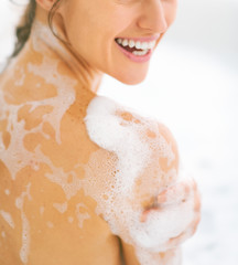 Closeup on happy young woman washing in bathtub