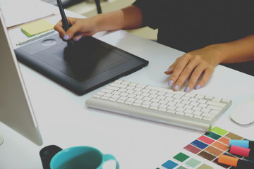 Young asian graphic designer working on computer using digital tablet at office.