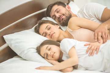 The happy family sleeping on the comfortable bed