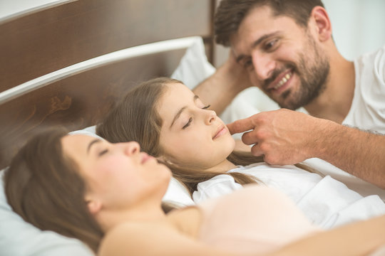 The little girl sleeping near the parents in the bed