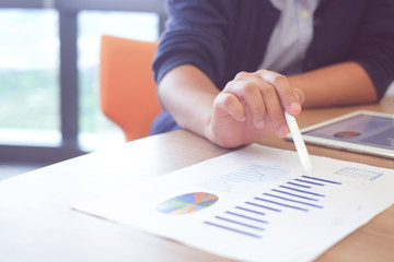 close up businesswoman hand holing stylus pen and pointing on statistic stock graph profit paper...