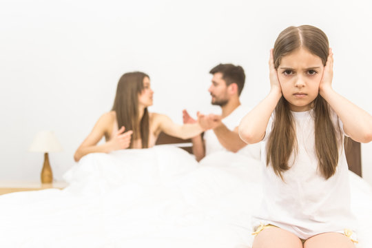 The unhappy girl sit on the background of the arguing parents