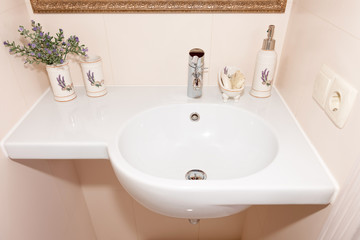 Fragment of a luxury bathroom. Exclusive modern white bathroom with white sink and faucet.