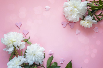 Romantic background with white peonies and decorative hearts on a pink.