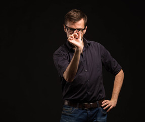 Young pensive man portrait of a confident businessman showing by hands placard black background. Ideal for banners, registration forms, presentation, landings, presenting concept.