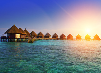 houses over the transparent quiet sea water  on a sunset. Maldives..