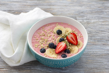 Smoothie bowl with sprouted green buckwheat, strawberries, blueberries and bananas on a wooden table