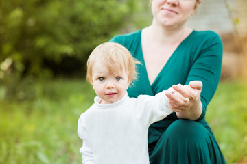 Cute little girl with big eyes standing in front of mom and holding her hand