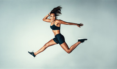 Female model in sports wear jumping in air - obrazy, fototapety, plakaty